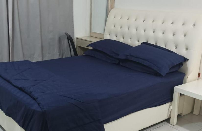 1 cama con edredón y almohadas azules en D CAMYLIA PUTRAJAYA HOMESTAY, en Putrajaya