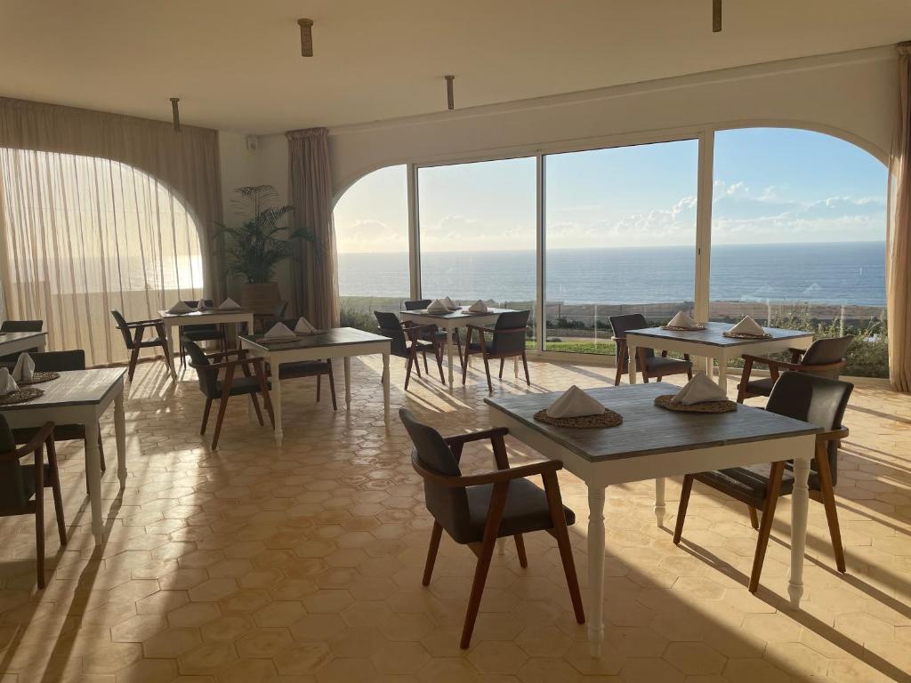 a restaurant with tables and chairs and a view of the ocean at Villa La Falaise in Oualidia
