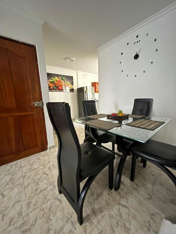 ein Esszimmer mit einem Tisch, Stühlen und einer Uhr in der Unterkunft Apartamento Vacacional Cartagena Colombia in Cartagena de Indias