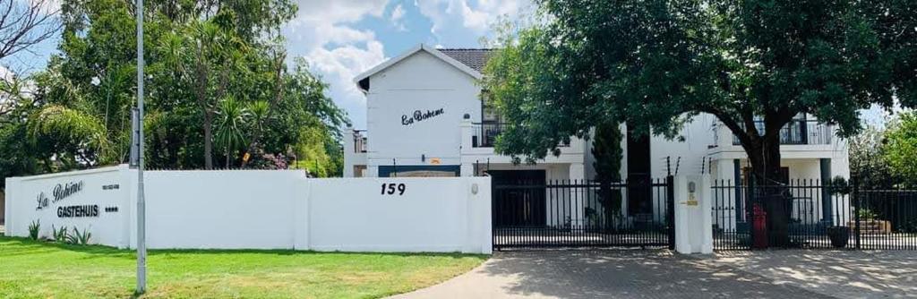 Biały dom z bramą przed nim w obiekcie La Bohéme Gastehuis w mieście Bloemfontein