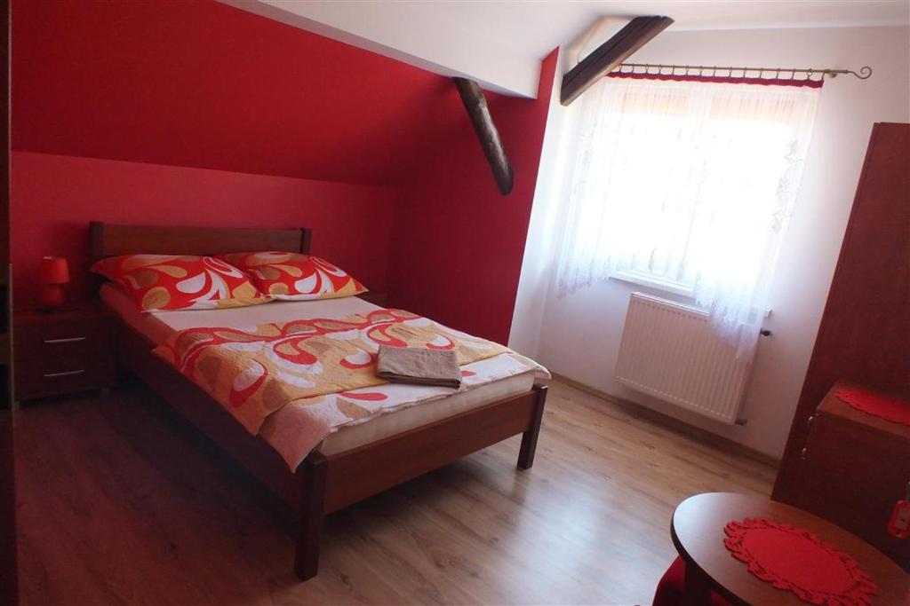 ein rotes Schlafzimmer mit einem Bett mit einem Buch darauf in der Unterkunft Dom Na Leśnej Górze in Leśna