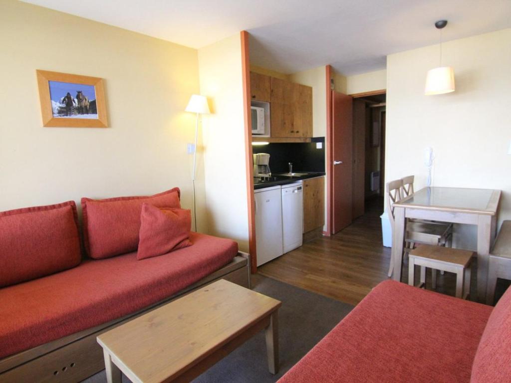 un salon avec un canapé rouge et une cuisine dans l'établissement Studio cosy 4 pers à l'Alpe d'Huez – Balcon sud, proche pistes et commerces, animaux acceptés - FR-1-405-152, à L'Alpe-d'Huez