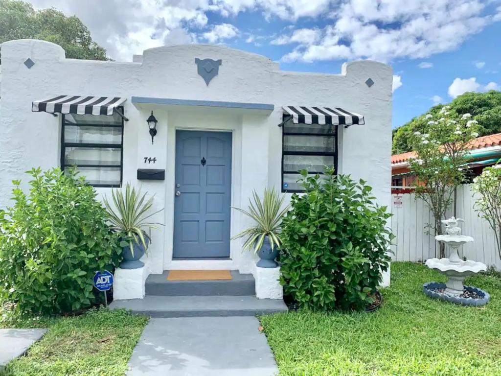 una casa blanca con una puerta azul en Cozy rooms in cute house, close to Miami airport - Free parking en Miami
