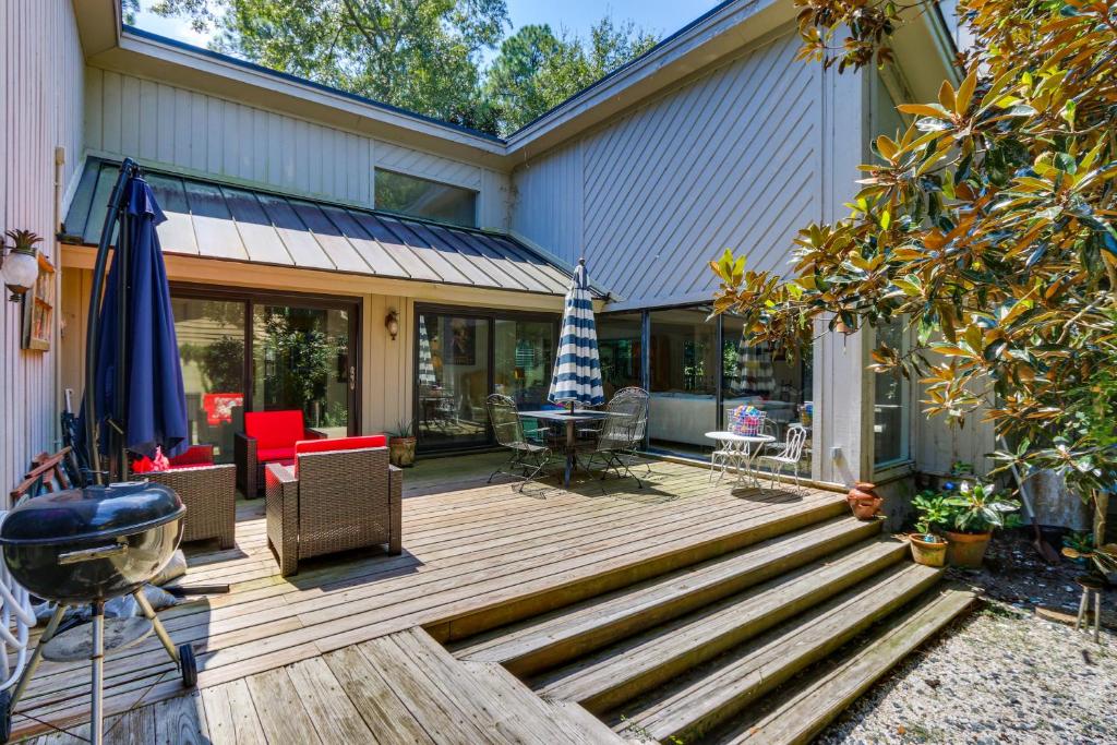a wooden deck with chairs and an umbrella on a house at Bright Hilton Head Cottage with Deck about 2 Mi to Beach in Hilton Head Island