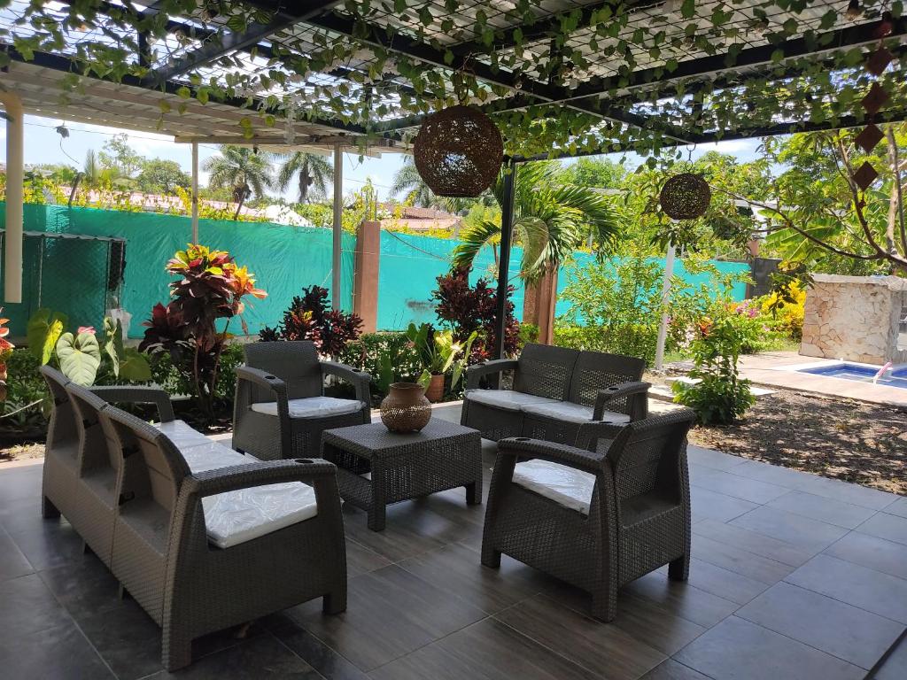 eine Terrasse mit Stühlen, Tischen und einer Pergola in der Unterkunft Casa Hotel el Encanto de Carmen 