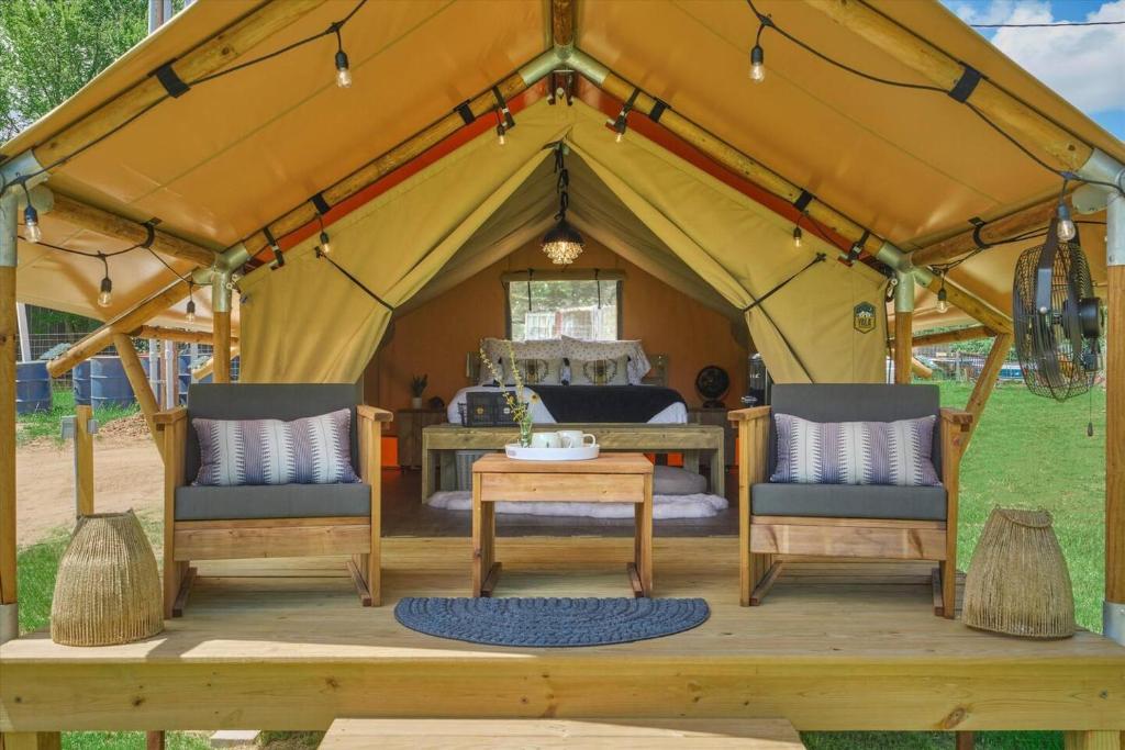 a tent with a bed and two chairs and a table at BeeWeaver Luxury Glamping - In A Meading in Navasota