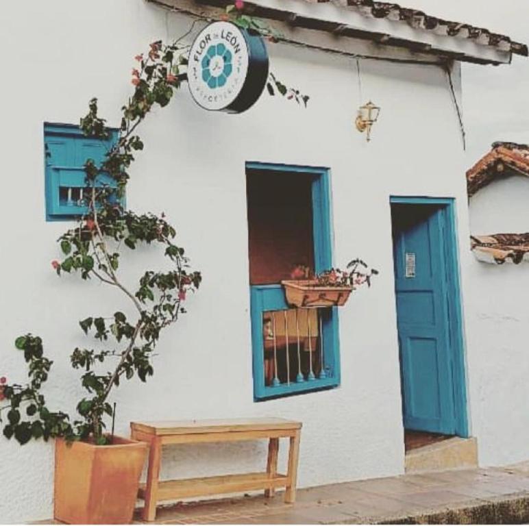 巴里查拉的住宿－Flor de León Café - Hostal，白色的建筑,设有蓝色的窗户和长凳