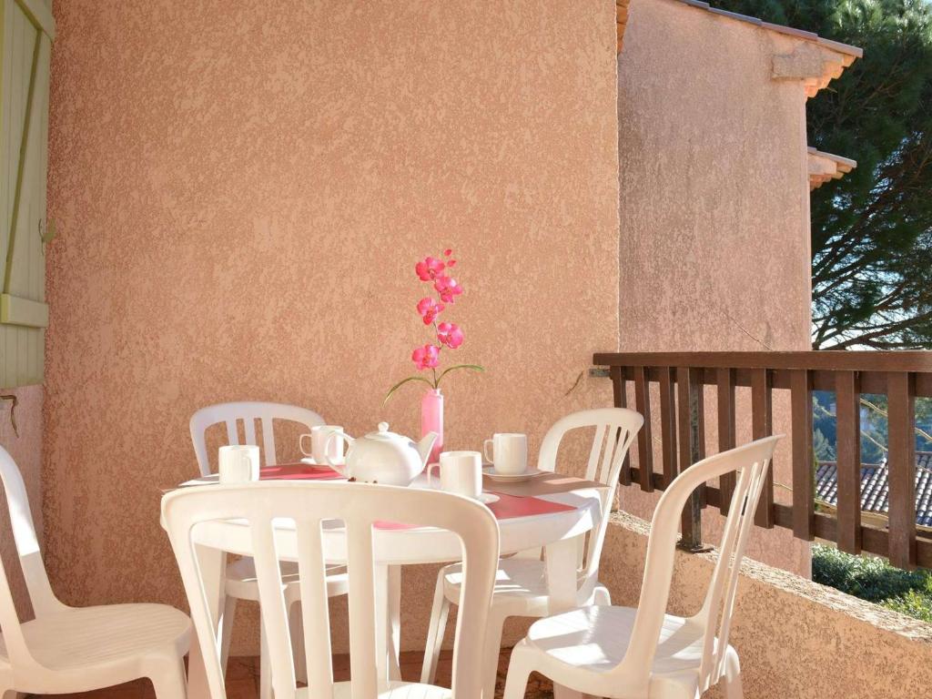 une table blanche avec des chaises blanches et un vase avec des fleurs roses dans l'établissement Appartement 6 couchages avec piscine et parking aux Issambres - FR-1-226-386, aux Issambres