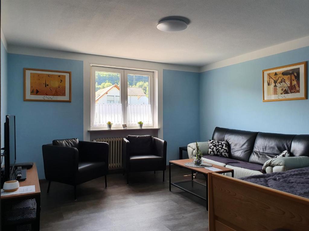 ein Wohnzimmer mit blauen Wänden, einem Sofa und Stühlen in der Unterkunft Ferienwohnung Paul in Losheim