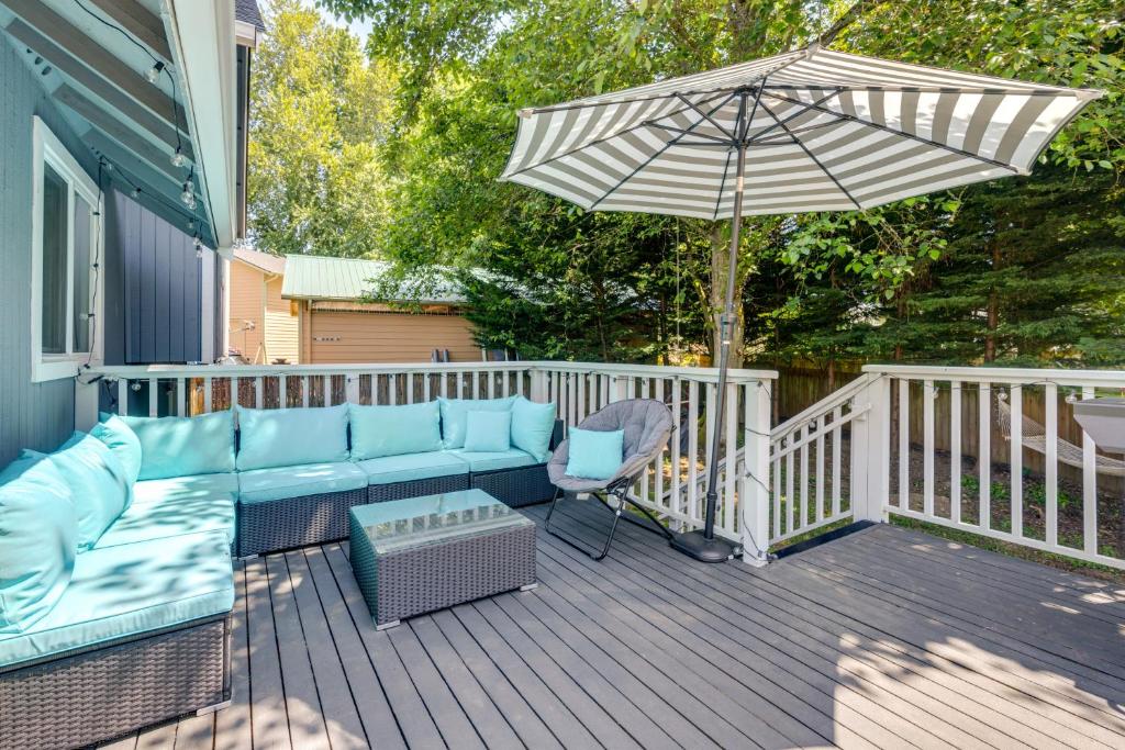 a patio with a couch and an umbrella on a deck at Lynwood Vacation Rental with Outdoor Living Galore! in Lynnwood