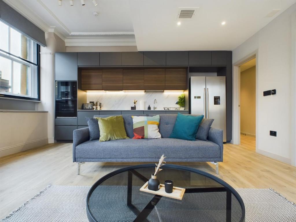 Classy 2bedroom City Centre Apt في مانشستر: غرفة معيشة مع أريكة زرقاء وطاولة زجاجية