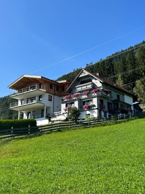 a building on a hill with a green field at Appartement Fischbacher in Schladming