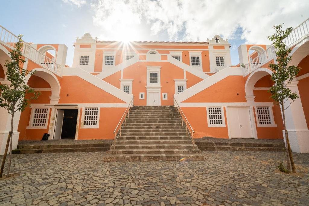 Un grand bâtiment orange avec des escaliers se trouve juste devant. dans l'établissement Palacio Santa Catarina Hotel, à Angra do Heroísmo