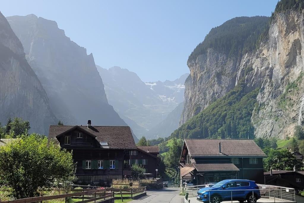 un coche azul estacionado frente a una montaña en Staubbach View - Traditional Chalet Apartment en Lauterbrunnen