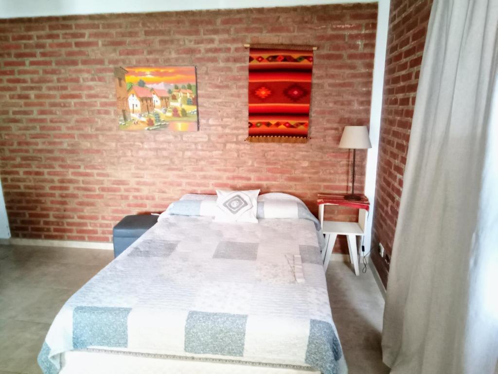 Monoambiente las lilas في بويرتو مادرين: غرفة نوم بسرير وجدار من الطوب