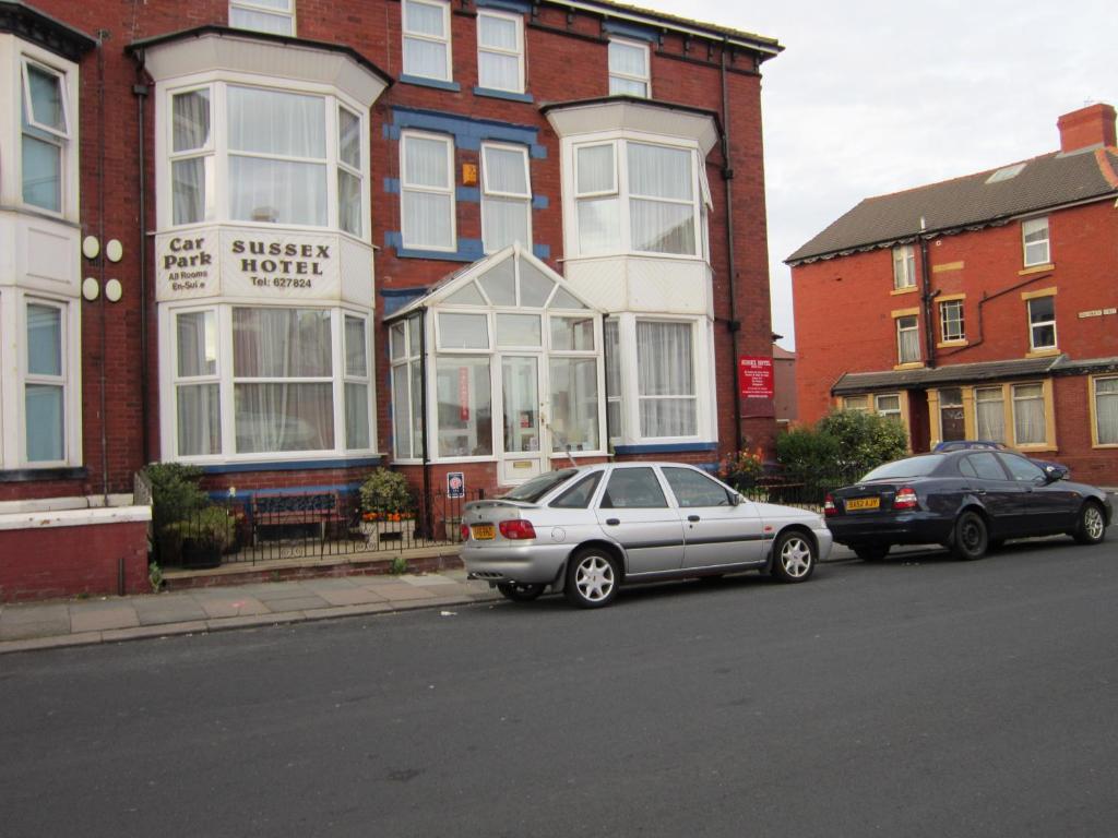 two cars parked on the street in front of a building at Sussex Hotel in Blackpool
