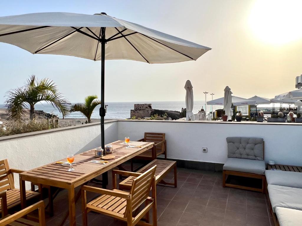 a patio with a table with an umbrella and the beach at Casa Mirador del Castillo in Cotillo