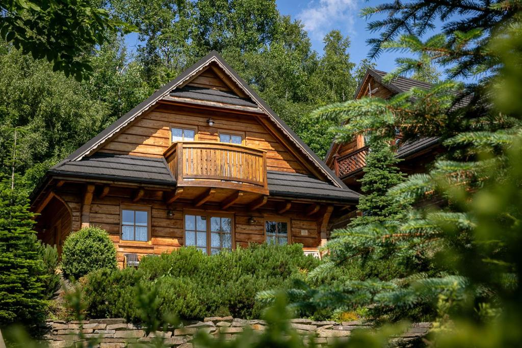 um chalé de madeira com uma varanda em cima em Kotelnica Resort em Miedzybrodzie Bialskie