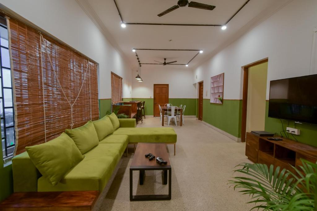 a living room with a green couch and a table at Snore Summore, Hostel in Koramangala in Bangalore