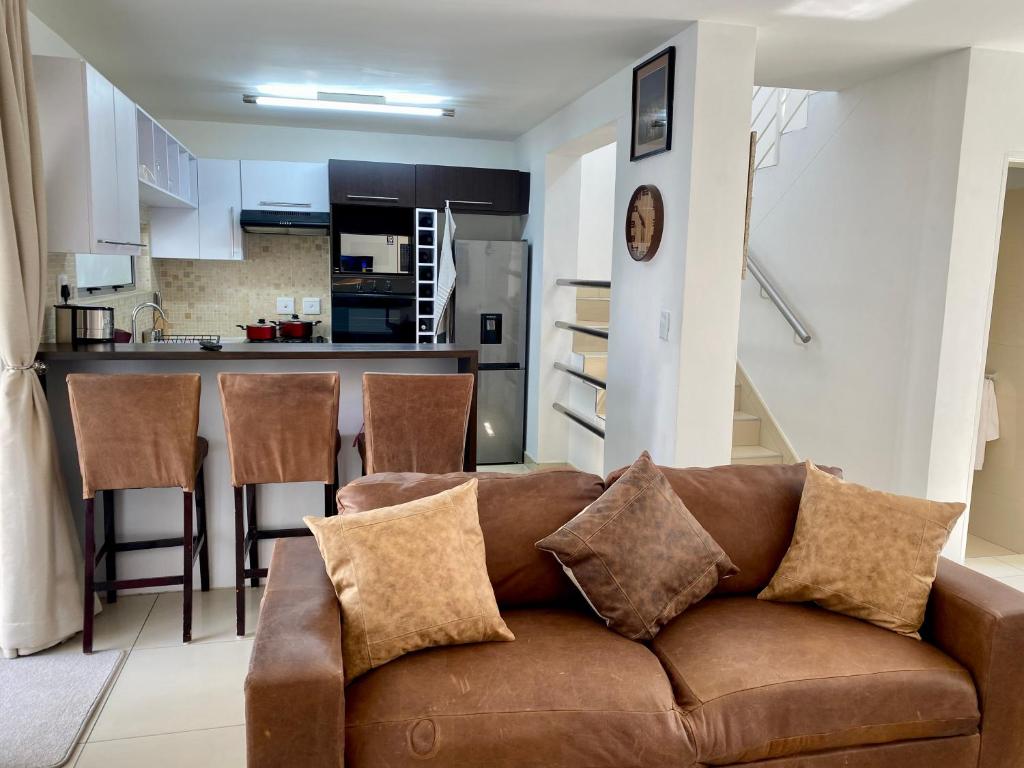 sala de estar con sofá marrón y cocina en Catalea's Cousy home en Windhoek