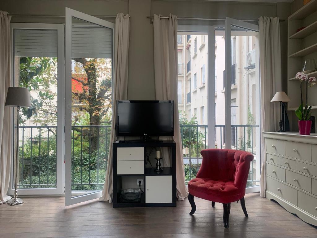 ein Wohnzimmer mit einem TV und einem roten Stuhl in der Unterkunft Porte Maillot-Charming and calm studio at Neuilly in Neuilly-sur-Seine
