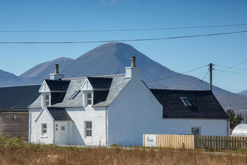 a white house with a mountain in the background at Breakish Cottage in Breakish