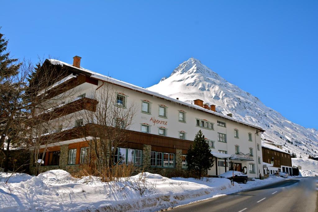 a hotel with a snow covered mountain in the background at Clubdorf Hotel Alpenrose in Galtür