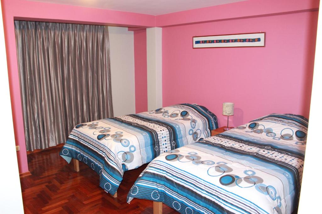 Cusco Apartment في كوسكو: سريرين في غرفة بجدران وردية