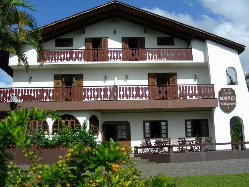 a large white building with balconies and tables at Hotel Bergblick in Pomerode