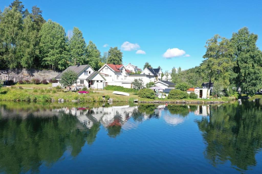 a house sitting next to a lake with houses at Hus i Telemarkskanalens hjerte in Ulefoss
