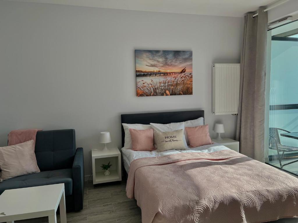 a bedroom with a bed and a couch at Studio Apartment Raspberry by Galeria Północna in Warsaw