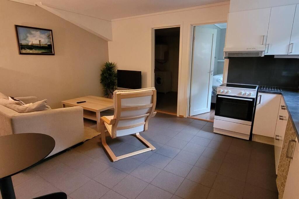 uma sala de estar com um sofá, uma mesa e uma cozinha em Cosy flat with 180cm wide very comfortable bed em Sandefjord