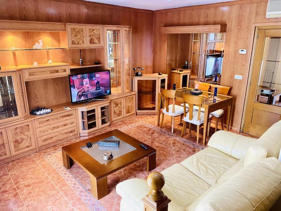 ein Wohnzimmer mit einer Couch, einem Fernseher und einem Tisch in der Unterkunft Dúplex pareado con zona exterior in Navalcarnero