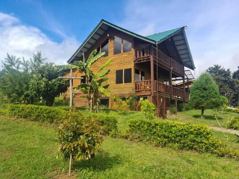 una casa de madera en una colina con césped verde en Cabaña Rancho Don Marino, en Cartago