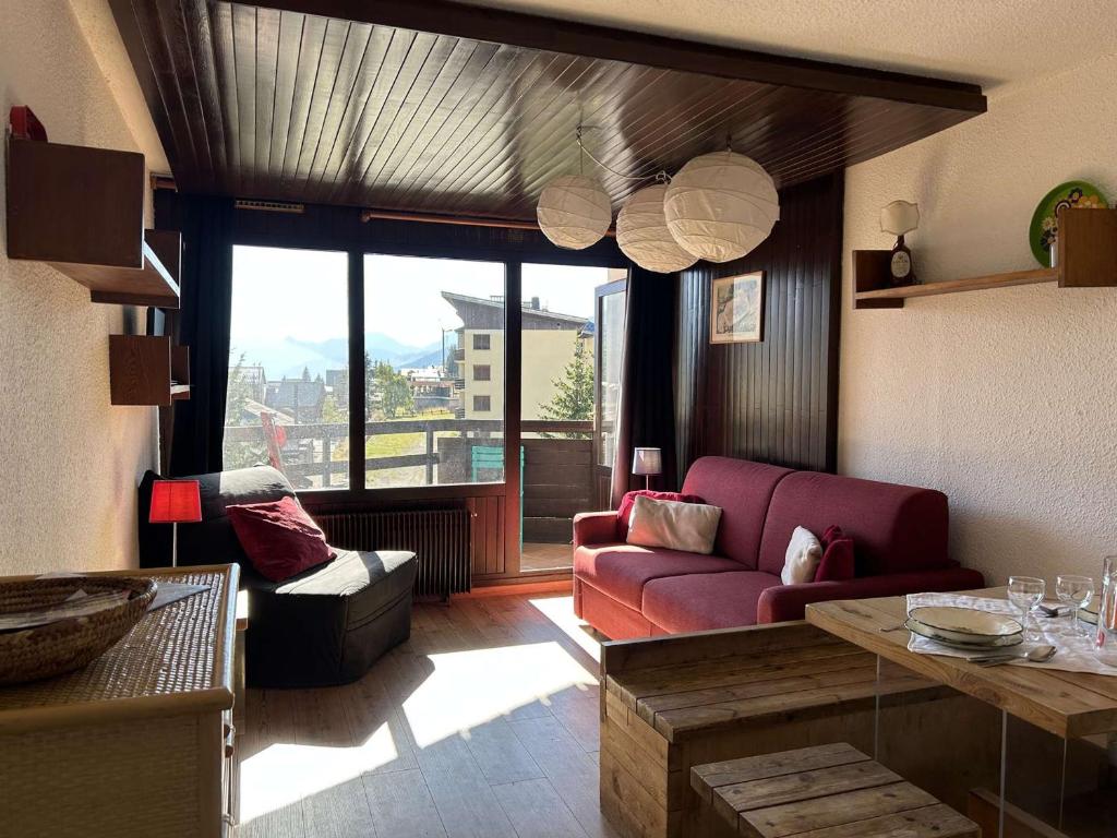 a living room with a red couch and a large window at Appartement Montgenèvre, 1 pièce, 2 personnes - FR-1-330D-84 in Montgenèvre