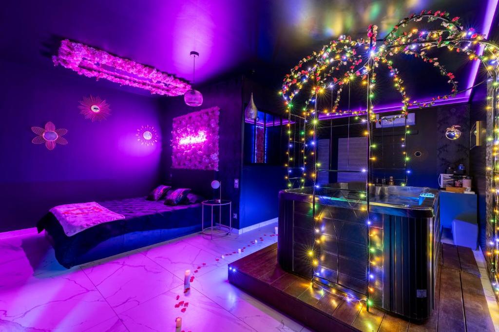 Dormitorio púrpura con cama y luces en Sweet SECRET'S JACUZZI, en Le Breuil