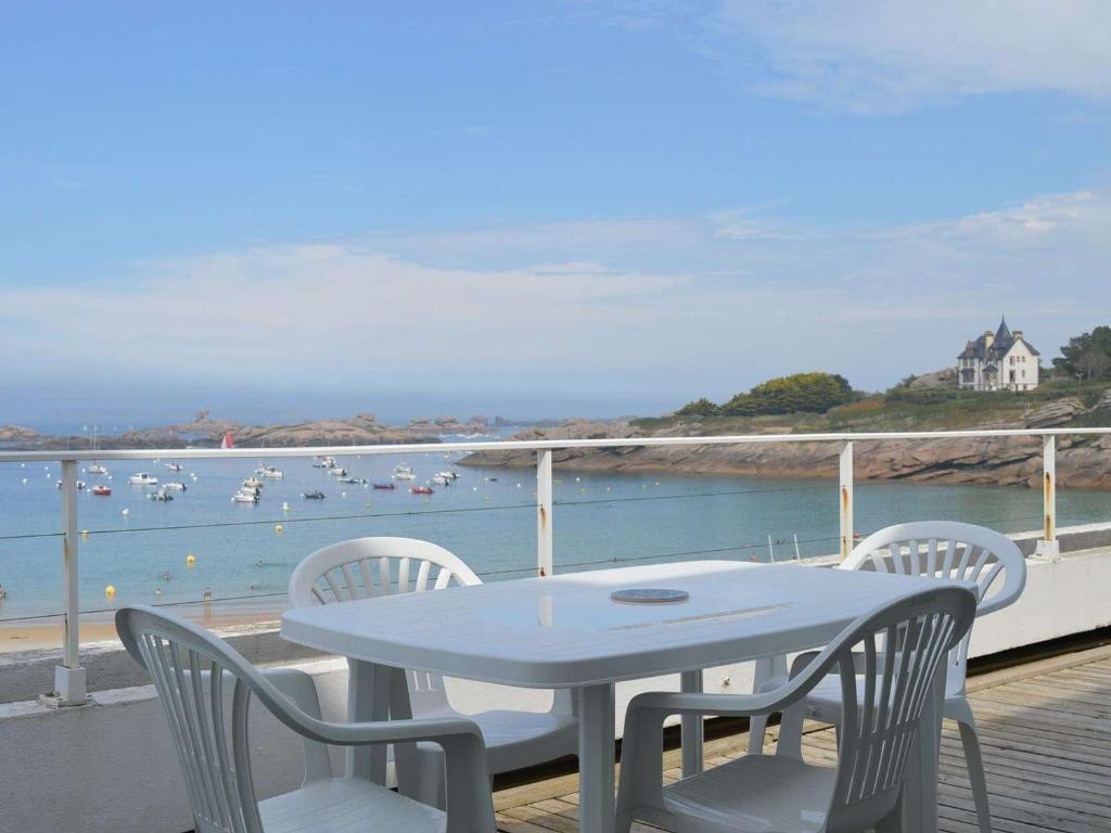 a table and chairs on a deck with a view of the water at Appartement Trégastel: Vue mer, Parking privé, Petit chien admis. - FR-1-542-5 in Trégastel