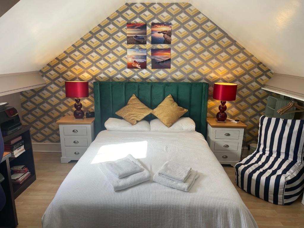 a bedroom with a bed with a green headboard and two chairs at Walpole House in London