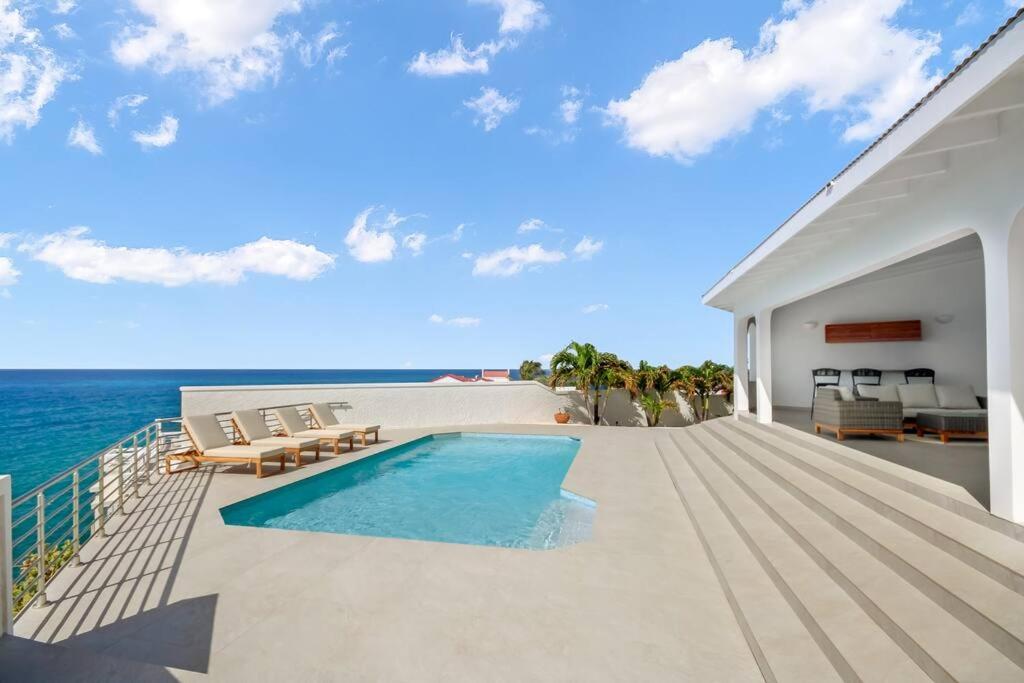 a house with a swimming pool next to the ocean at Puerta Al-Mar Villa in Simpson Bay