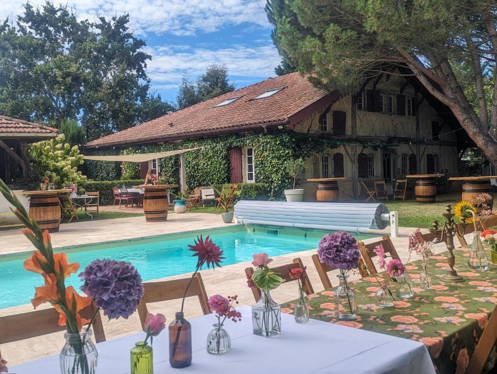 - une table avec des fleurs à côté de la piscine dans l'établissement Maison Pimoli : Chambre Hortense, à Soustons