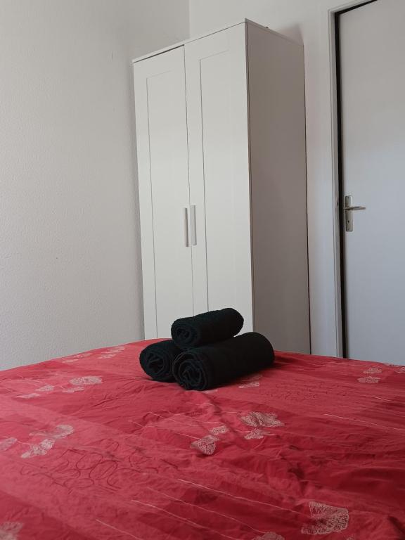 un par de toallas negras sentadas encima de una cama en Chez Fred, en Mordelles