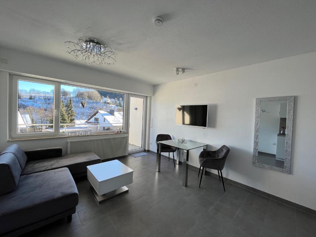 sala de estar con sofá, mesa y ventana en Kleiner Kristall inklusive MeineCard Plus en Willingen