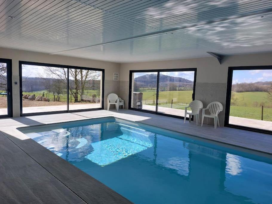una grande piscina in una casa con finestre di Gîte 15 p avec piscine intérieure 