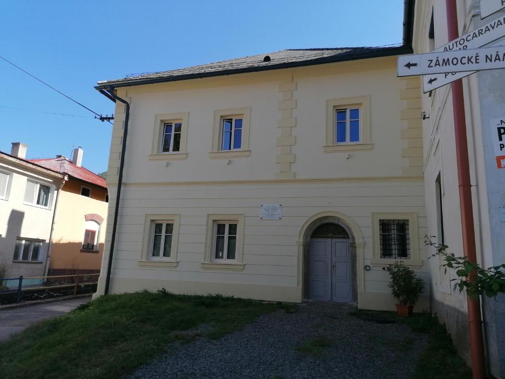 a white house with a blue door in a street at Križkov dom in Kremnica