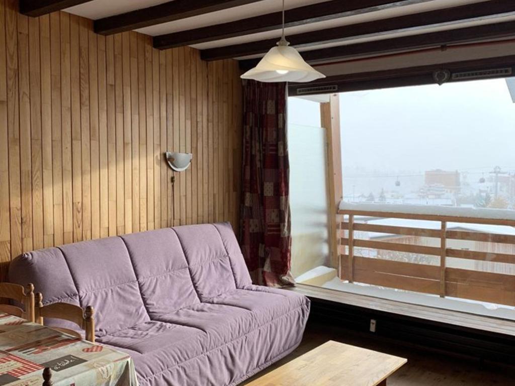 - un salon avec un canapé violet en face d'une fenêtre dans l'établissement Studio cosy pour 4 à L'Alpe d'Huez, balcon sud, proche pistes et commerces, animaux bienvenus - FR-1-405-197, à Huez