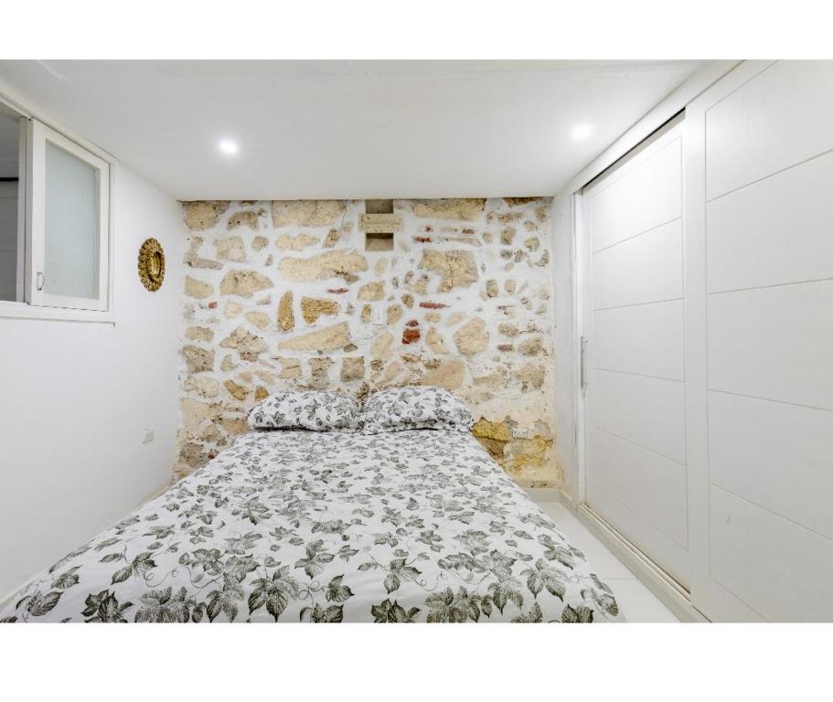 a bed in a room with a stone wall at Catedral in Cartagena de Indias