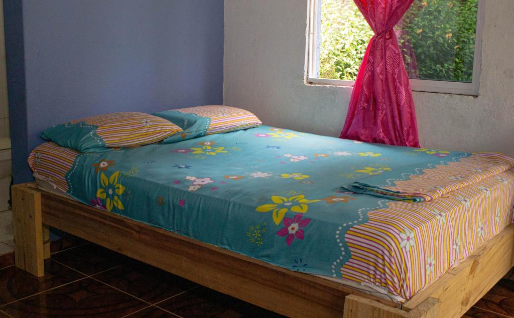 Bett mit blauer Decke und Fenster in der Unterkunft Cabañas yami in Playa Ladrilleros
