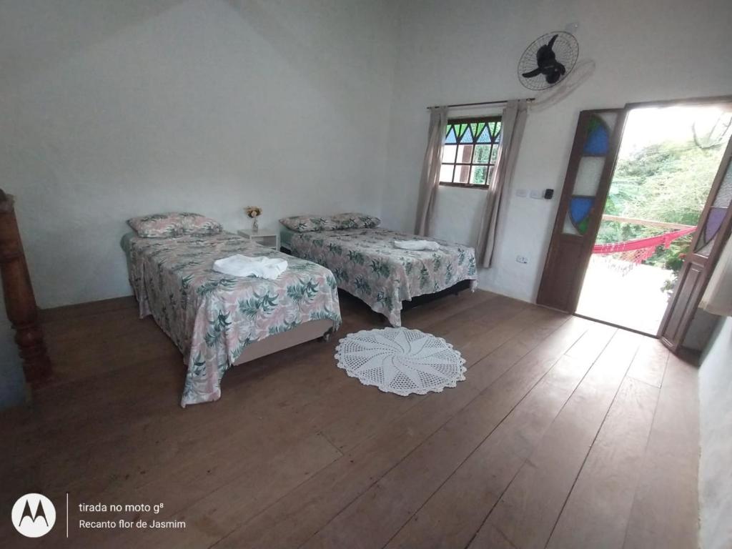 Habitación con 2 camas, mesa y ventana en Recanto Flor de Jasmim, en Ilhabela