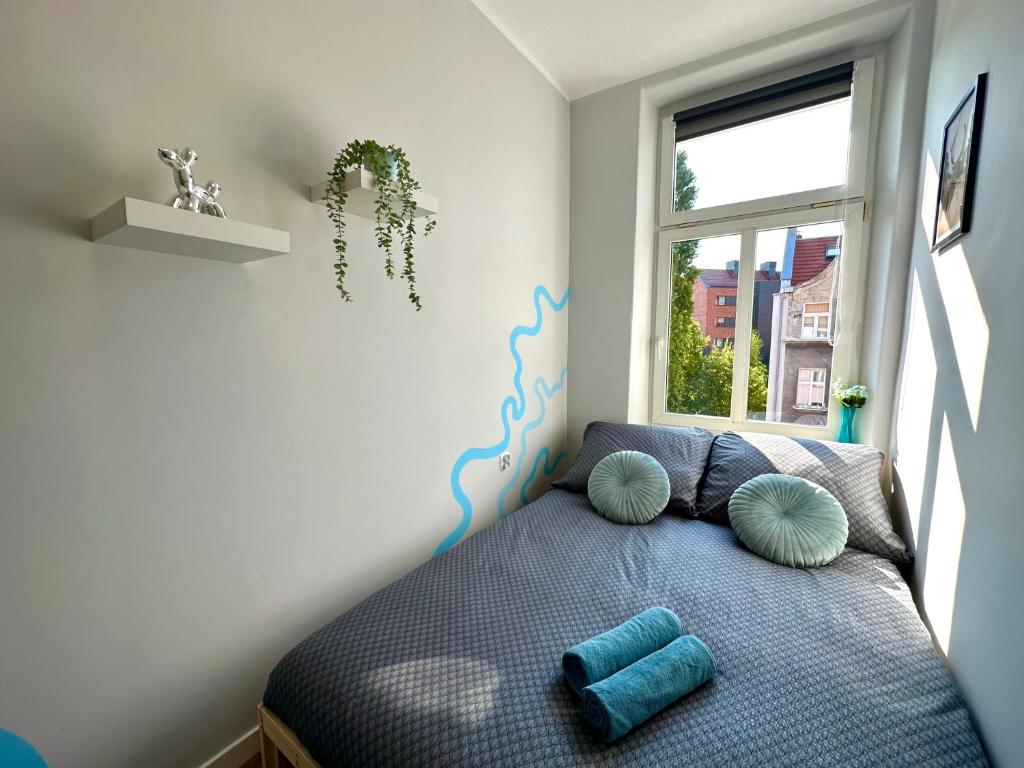 een slaapkamer met een bed met kussens en een raam bij MMRent Lady Blue Room in Gdańsk