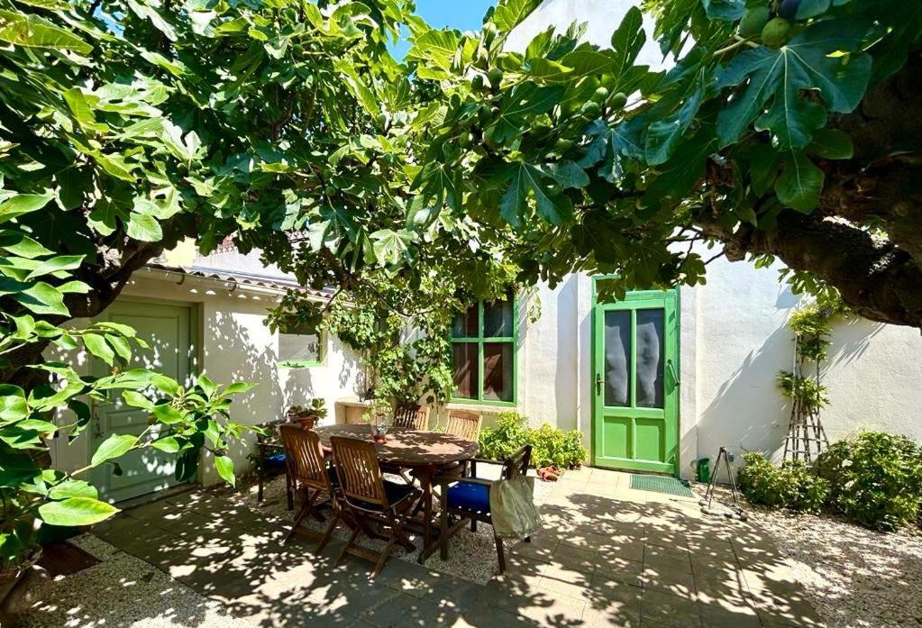 un patio avec une table et des chaises sous un arbre dans l'établissement Maison de charme en bord de Mer, au Barcarès
